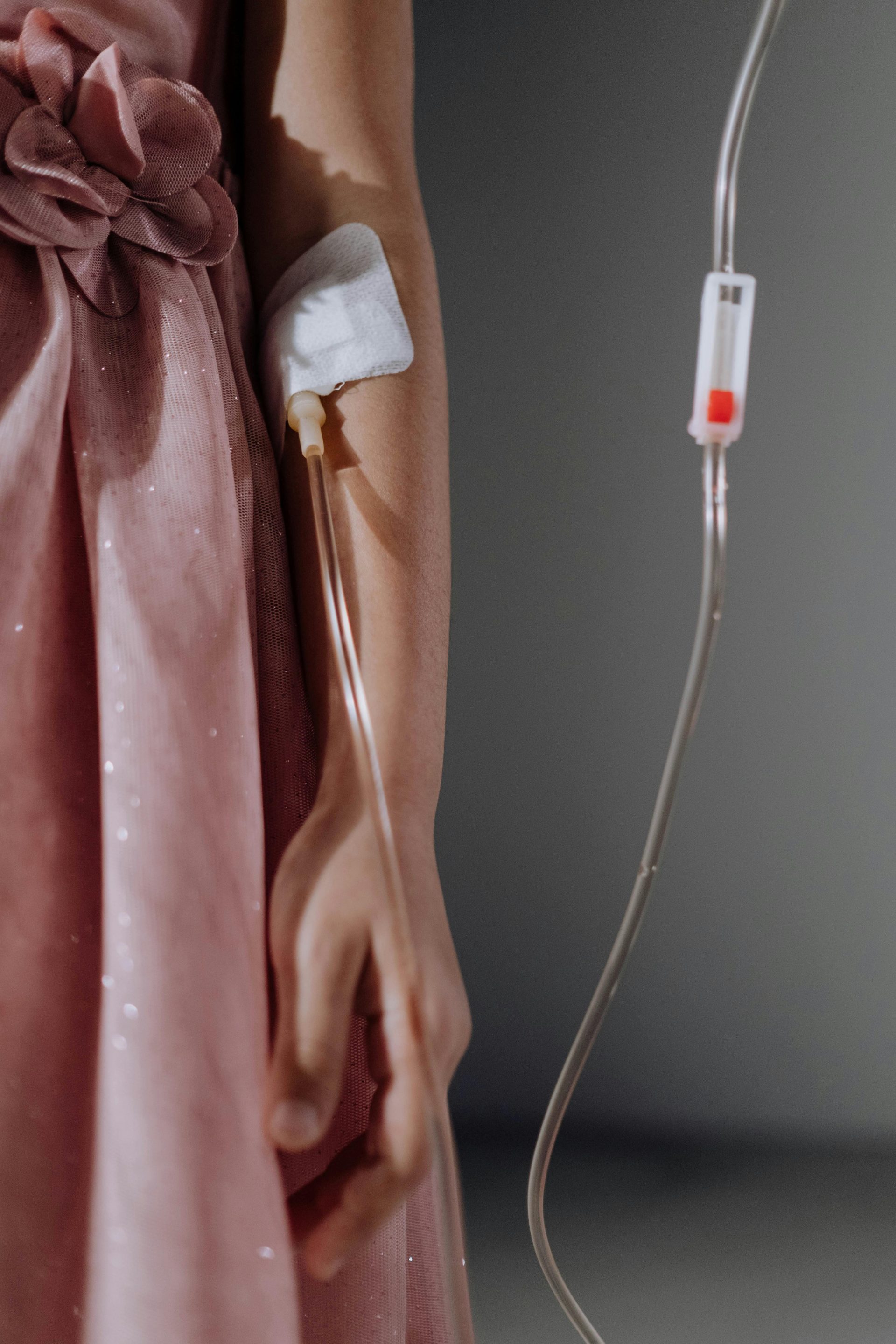 Close-up shot of a woman in a dress receiving intravenous therapy through her arm.
